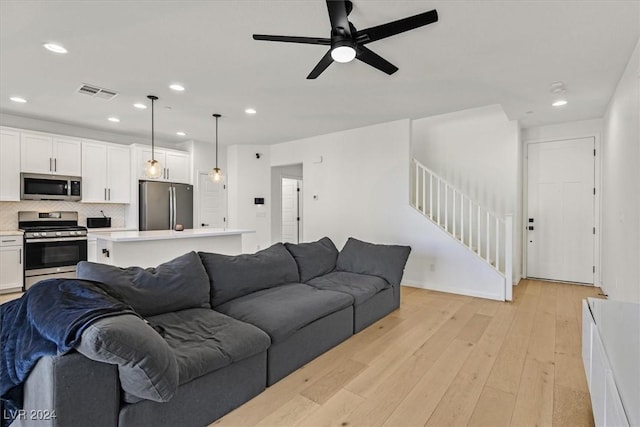 living room with light hardwood / wood-style flooring and ceiling fan