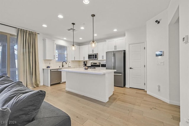 kitchen featuring appliances with stainless steel finishes, light hardwood / wood-style floors, a kitchen island, and pendant lighting