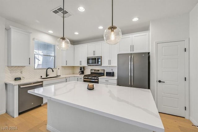 kitchen featuring appliances with stainless steel finishes, a center island, hanging light fixtures, and sink