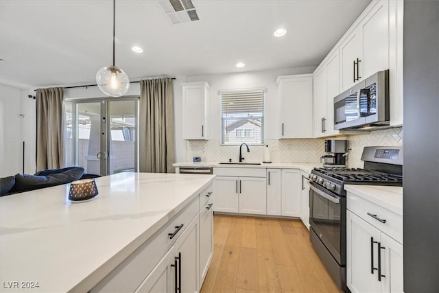 kitchen with white cabinetry, french doors, pendant lighting, appliances with stainless steel finishes, and light wood-type flooring