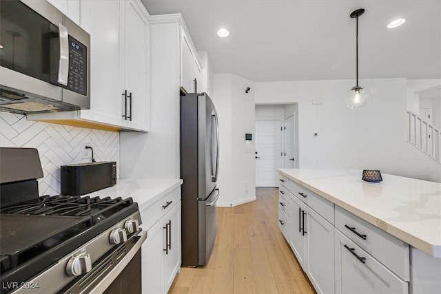 kitchen with hanging light fixtures, light stone countertops, appliances with stainless steel finishes, light hardwood / wood-style floors, and white cabinetry