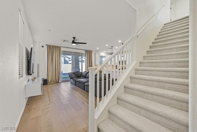 staircase with wood-type flooring and ceiling fan