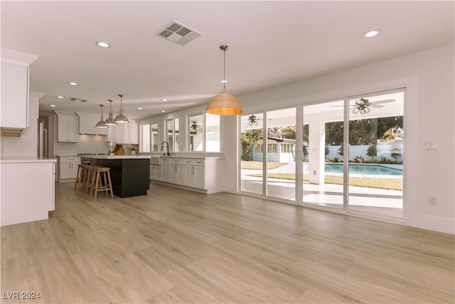 kitchen with decorative light fixtures, a center island, a breakfast bar area, and light hardwood / wood-style flooring