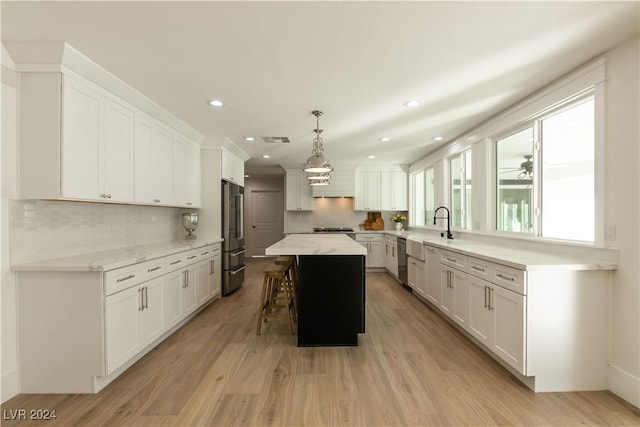 kitchen featuring light wood-type flooring, decorative light fixtures, a kitchen island, and tasteful backsplash