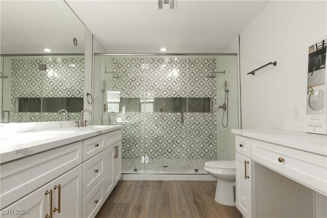 bathroom with hardwood / wood-style floors, vanity, an enclosed shower, and toilet