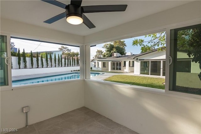 unfurnished sunroom with ceiling fan and a water view