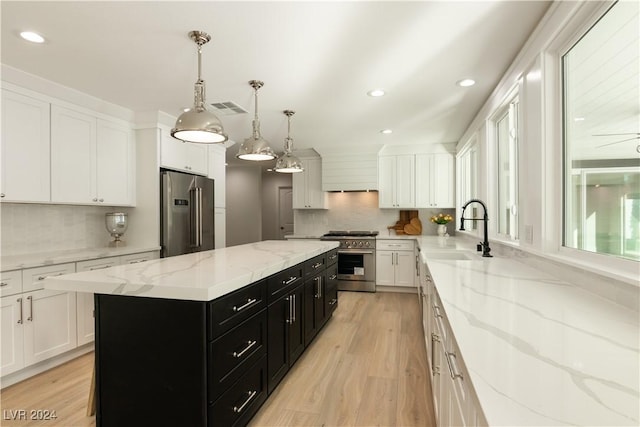 kitchen featuring sink, a center island, hanging light fixtures, white cabinets, and high end appliances