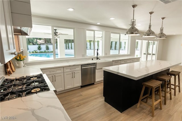 kitchen with dishwasher, light stone countertops, white cabinets, and a wealth of natural light