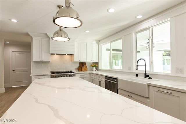 kitchen with backsplash, sink, hanging light fixtures, appliances with stainless steel finishes, and light stone counters