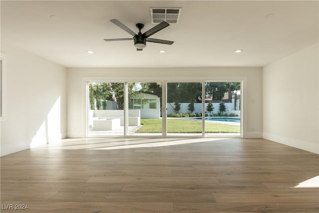 spare room with a wealth of natural light, ceiling fan, and hardwood / wood-style flooring