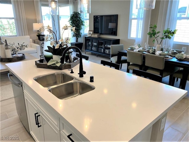 kitchen featuring dishwasher, sink, an island with sink, pendant lighting, and white cabinets