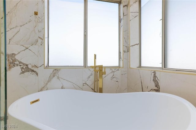 bathroom featuring tile walls and a tub