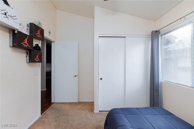 carpeted bedroom with lofted ceiling and a closet