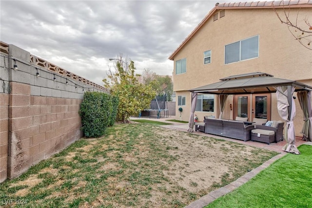 view of yard featuring outdoor lounge area, a gazebo, a trampoline, and a patio