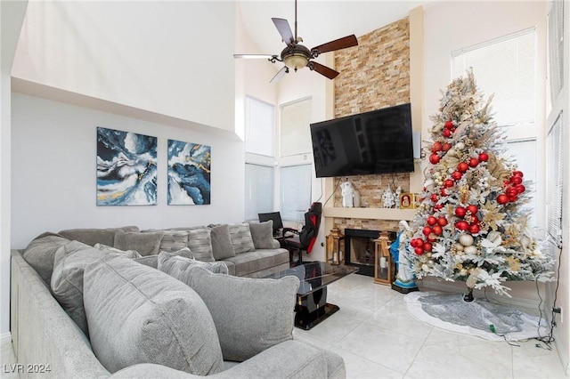 living room with tile patterned floors, ceiling fan, a fireplace, and a high ceiling