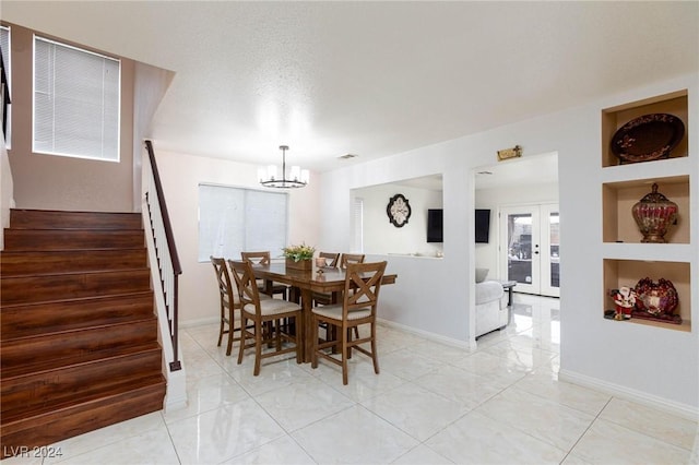 dining area with french doors, a textured ceiling, light tile patterned floors, built in features, and an inviting chandelier