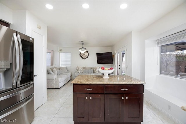 kitchen featuring stainless steel fridge, plenty of natural light, light tile patterned flooring, and light stone countertops