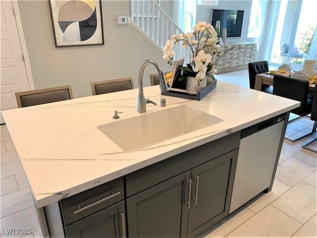 kitchen featuring a healthy amount of sunlight, sink, stainless steel dishwasher, and light stone counters