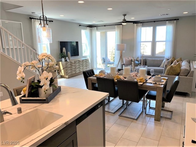 kitchen featuring stainless steel dishwasher, decorative light fixtures, sink, and a wealth of natural light