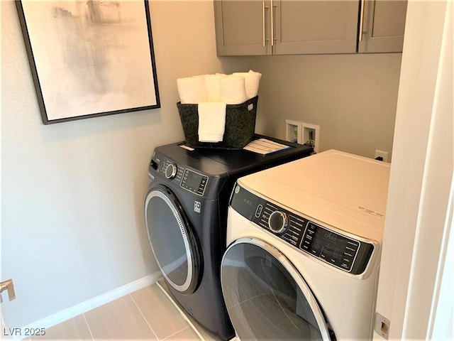 laundry area featuring cabinets, light tile patterned floors, and washing machine and clothes dryer