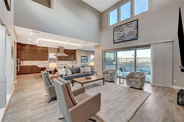 living room featuring light hardwood / wood-style flooring and a towering ceiling