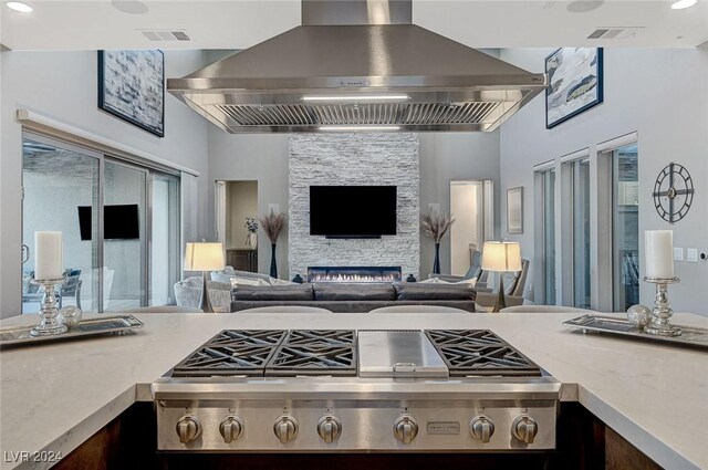 kitchen with a fireplace, stainless steel gas stovetop, and range hood