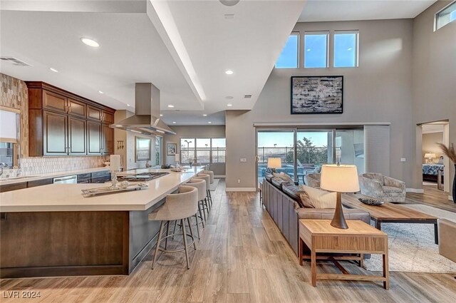 kitchen featuring a breakfast bar, a center island, sink, light hardwood / wood-style flooring, and island exhaust hood