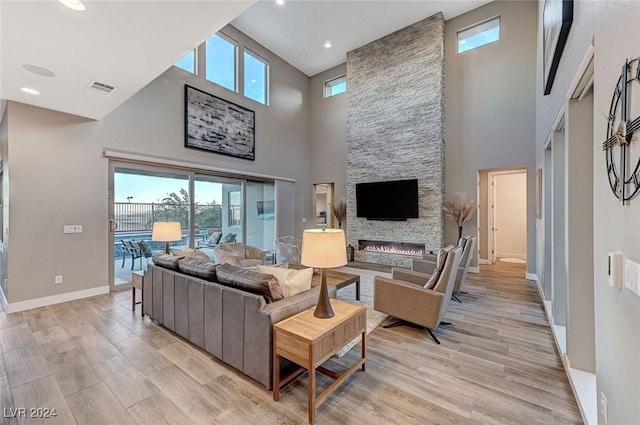 living area with light wood-type flooring, visible vents, a fireplace, and baseboards