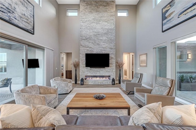 living room with a fireplace, a high ceiling, and a healthy amount of sunlight