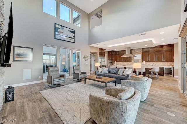 living room with light wood-type flooring, wine cooler, plenty of natural light, and baseboards