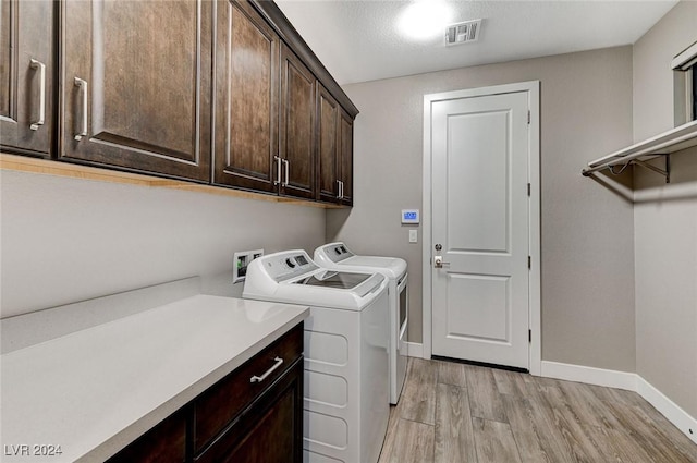 clothes washing area with cabinets, independent washer and dryer, and light hardwood / wood-style floors