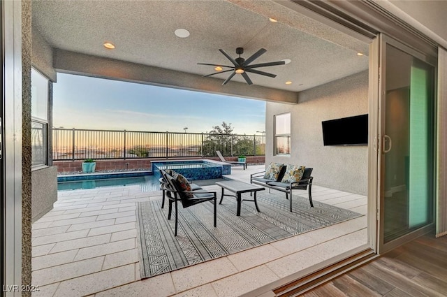 patio terrace at dusk featuring a ceiling fan, fence, and a fenced in pool