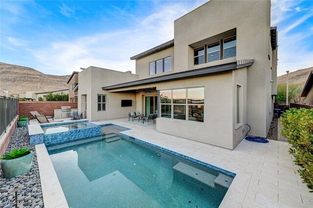 back of house with a mountain view, ceiling fan, a patio area, and a pool with hot tub