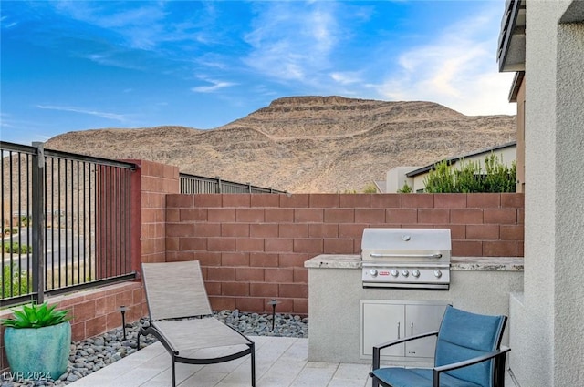 view of patio with exterior kitchen, a mountain view, area for grilling, and fence