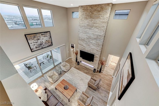 living room with a towering ceiling, a fireplace, and light hardwood / wood-style flooring