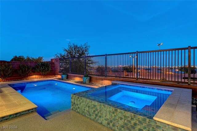 pool at dusk with an in ground hot tub