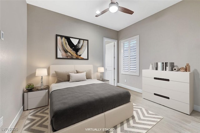 bedroom with a ceiling fan, light wood-style flooring, and baseboards