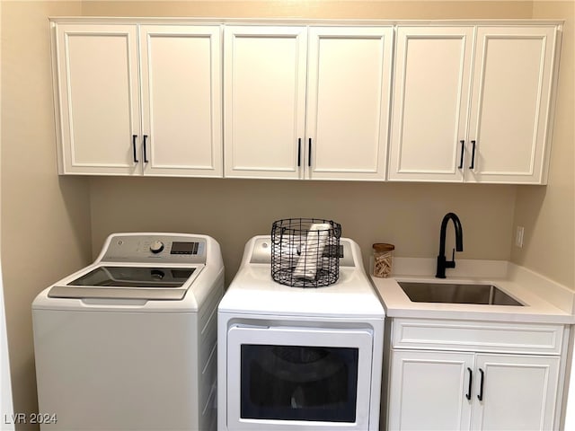 laundry room featuring washer and clothes dryer, sink, and cabinets