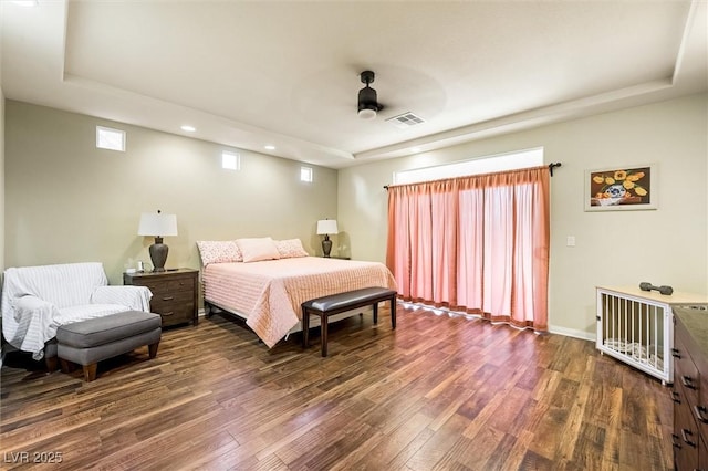 bedroom featuring a raised ceiling, ceiling fan, and dark wood-type flooring