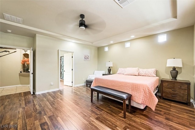 bedroom with ceiling fan, dark hardwood / wood-style flooring, and a tray ceiling