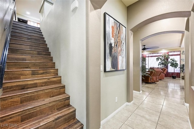 staircase featuring tile patterned flooring and ceiling fan