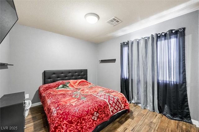 bedroom with dark hardwood / wood-style flooring and a textured ceiling