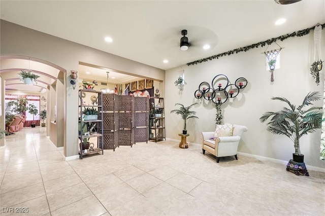 living area with light tile patterned floors and ceiling fan