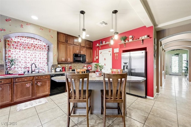 kitchen featuring a center island, black appliances, sink, hanging light fixtures, and tasteful backsplash