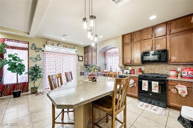 kitchen with a center island, hanging light fixtures, a breakfast bar area, and black appliances