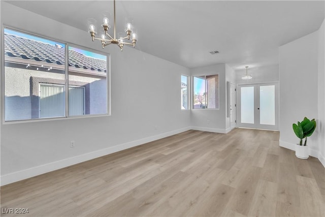 interior space with french doors, light hardwood / wood-style floors, and an inviting chandelier