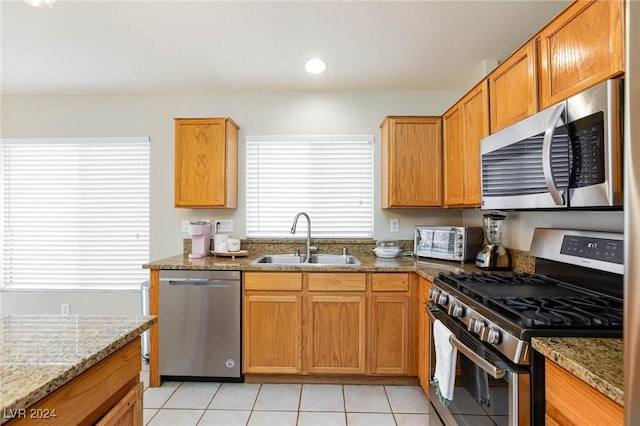 kitchen featuring light stone counters, sink, light tile patterned floors, and stainless steel appliances