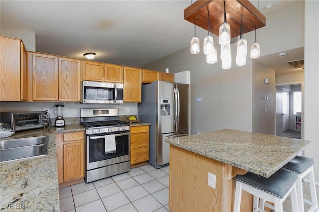 kitchen with light stone countertops, decorative light fixtures, a breakfast bar area, light tile patterned flooring, and appliances with stainless steel finishes