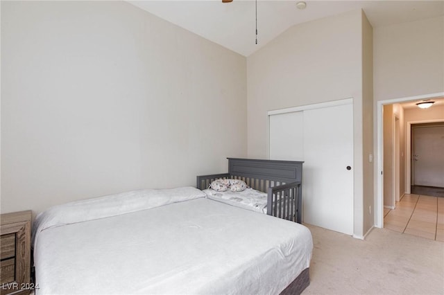 bedroom with light colored carpet, high vaulted ceiling, and a closet