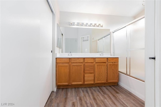 bathroom featuring hardwood / wood-style floors, vanity, and combined bath / shower with glass door